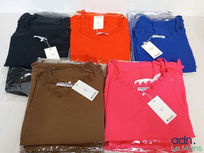 six t-shirts de couleurs différentes, dans des sacs en plastique, posés sur une surface blanche