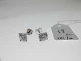 une paire de boucles d'oreilles en argent et une étiquette de prix posée sur une table blanche