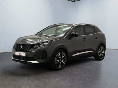 Une voiture grise est garée dans une grande pièce au sol noir.