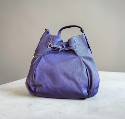 un sac à main violet posé sur une table près d'un mur