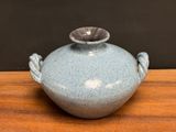 a blue vase sitting on a wooden table with a black background