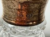 a glass vase with a metal lid on a table