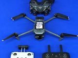 a black and white drone and a cell phone on a blue surface