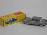 grey toy car in front of a yellow box on a white surface