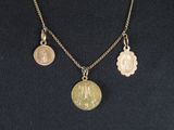 a close up of a necklace with a coin and two charms on it