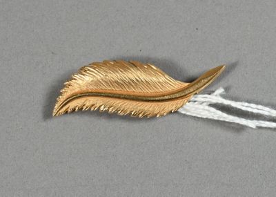 une feuille d'or suspendue à un fil blanc sur une surface grise