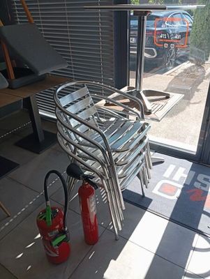 une chaise et un extincteur posés devant une porte vitrée