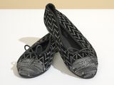une paire de chaussons noirs et blancs posés sur une surface blanche