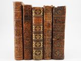 several old books are lined up in a row on a white surface