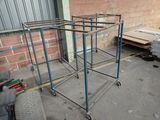 a metal rack that has wheels on it in front of a brick wall