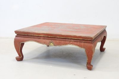 a small wooden table with a red top on a white floor