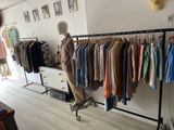 a photo of a clothing store with a mannequin in front of a rack of clothes