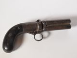 un vieux pistolet posé sur une surface blanche, avec une crosse noire