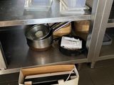 une étagère métallique avec des casseroles et des poêles dans une cuisine