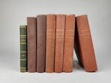 several old books are stacked on top of each other on a white surface