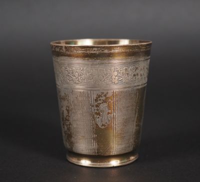 une coupe ancienne en argent posée sur une surface noire, avec un fond noir