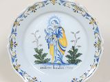 une assiette bleue et jaune sur laquelle est représentée une femme tenant un bébé dans ses bras