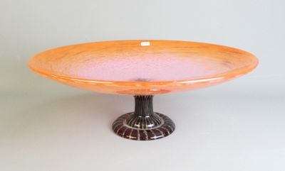 un bol en verre orange posé sur un socle en métal noir