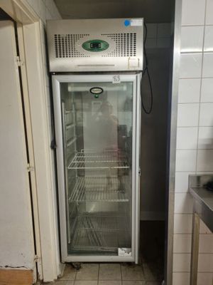 a refrigerator that is open in a kitchen with tile flooring