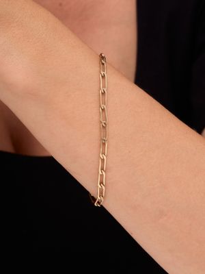 a close up of a woman ' s arm wearing a gold chain bracelet