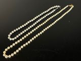 a white pearl necklace with a gold clasp on a black surface