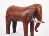 a small wooden elephant that is standing on a white surface