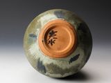 a green vase with a brown lid on a white surface