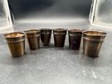 six verres à shot en laiton vieilli alignés sur une table
