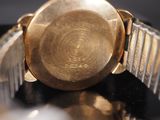 a close up of a gold watch on a black surface