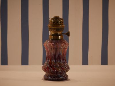 a red glass bottle with a gold top on a table