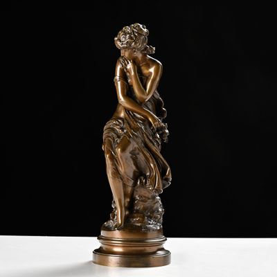 a bronze statue of a woman sitting on a rock