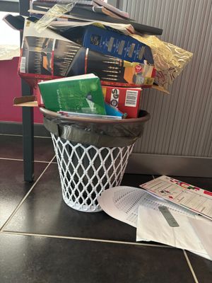 une poubelle remplie de livres et de papiers posée par terre