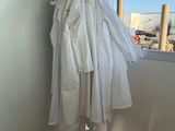 a white shirt hanging on a clothes rack next to a pair of white shoes