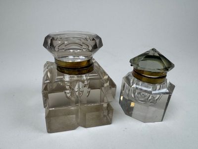 une paire de flacons de parfum en verre transparent posés sur une surface blanche