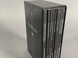 four books in a black box sitting on top of a white surface