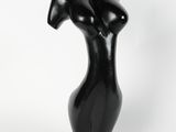 une sculpture noire représentant le torse d'une femme, posée sur un socle noir