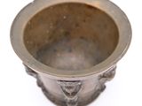 a small metal bowl with a handle on a white surface