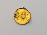 a close up of a gold coin with a pin on it