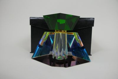 une image représentant un objet en verre vert et noir posé sur une surface blanche