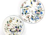 two plates with designs of birds and flowers on them on a white surface
