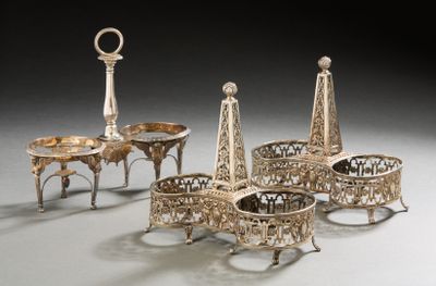 several pieces of silverware on a table with a clock in the background