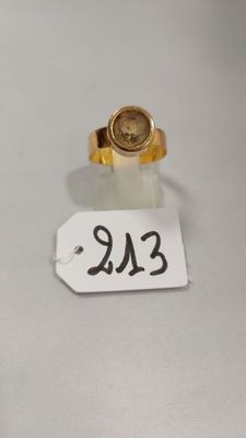 une petite bague en or surmontée d'une petite pièce en or