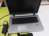 a laptop computer sitting on a desk with a charger and a cell phone