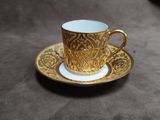 a gold cup and saucer on a brown table