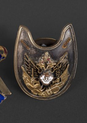 two pieces of metal with a cross and a shield on a black surface