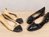 two pairs of black and beige shoes sitting on top of a wooden table