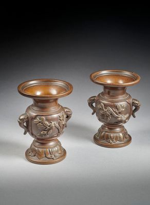 paire de vases en bronze munis d'anses, posés sur des socles, sur un fond gris