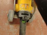 a yellow drill on the floor next to a black pole