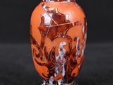 a small vase with a painting on it on a black surface