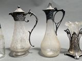 three glass vases and two silver vases on a table